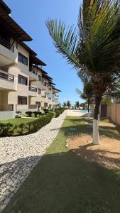 a palm tree in front of a building at Apartamento - Garden Flat Mar Azul in Taíba