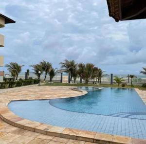 a swimming pool with palm trees and the ocean at Apartamento - Garden Flat Mar Azul in Taíba