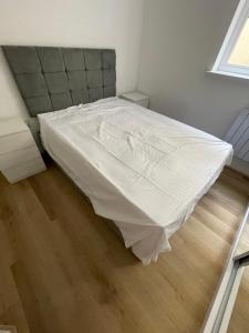 a bedroom with a bed with a white bed sheet at Woodlands in Wythenshawe