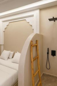a bedroom with a white bed and a wooden ladder at Soho elegance near beach & center 2 bedrooms terrasse in Essaouira