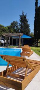 a pool with several wooden benches and a house at Quinta RASPANDO in La Reja +10 photos