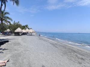 einen Strand mit Strohschirmen und dem Meer in der Unterkunft Escápate y convierte tus vacaciones en recuerdos in Santa Marta