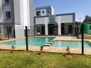 a fence in front of a building with a swimming pool at Naledi Inn in Gaborone