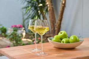 two glasses of white wine next to a bowl of apples at The Loft Apartment in Gaborone in Gaborone