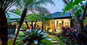 a house with palm trees in front of a yard at Balinese Inspired Luxury Villa in Playa Avellana
