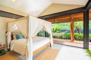 a bedroom with a canopy bed and a balcony at Balinese Inspired Luxury Villa in Playa Avellana +48 photos