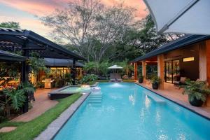 a swimming pool in front of a house at Balinese Inspired Luxury Villa in Playa Avellana