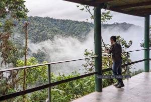 a man standing on a balcony looking at the mountains at Mashpi Amagusa Lodge in Mashpi +11 photos