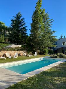a swimming pool in a yard with chairs and trees at Altos del Oeste in Villa Carlos Paz +34 photos