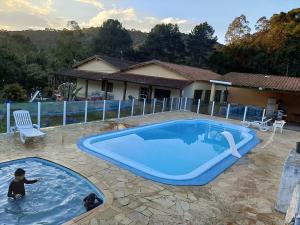 a pool with two children playing in the water at Sítio Jorema in Camanducaia