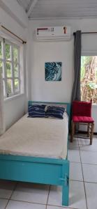 1 dormitorio con 1 cama azul y 1 silla roja en Apartamento dos coqueiros Búzios, en Búzios
