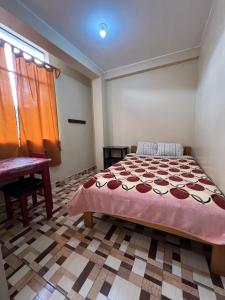 a bedroom with a bed and a table and a window at Curahuasi Backpackers in Curahuasi