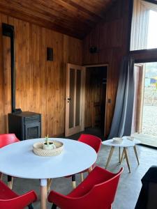 a room with a white table and red chairs at Cabaña - 5to Rincon Meliquina Home in Villa Meliquina +30 photos