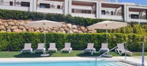 Un grupo de sillas y sombrillas junto a una piscina. en Newly built townhouse with spectacular sea views in an idyllic setting just 15 min from Marbella, en Istán