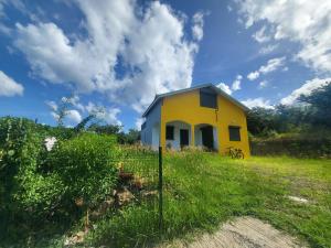 a yellow house in the middle of a field at Chambre indépendante calme pour femmes, en forêt, 1km plage in Deshaies