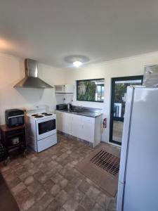 a kitchen with a white stove and a refrigerator at Classic Kiwi Beach Batch in Tapu