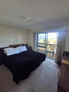 a bedroom with a bed and a large window at Classic Kiwi Beach Batch in Tapu