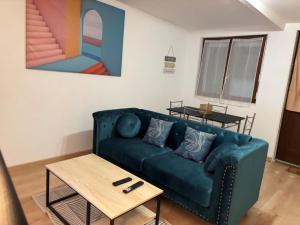 a living room with a blue couch and a table at Marcory, proche aéroport in Tillé
