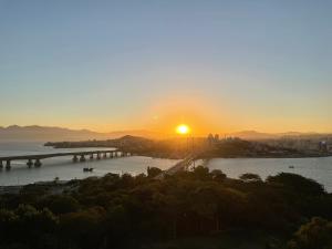 a sunset over a bridge over a river at Central Park Flat Residence - Home Time in Florianópolis