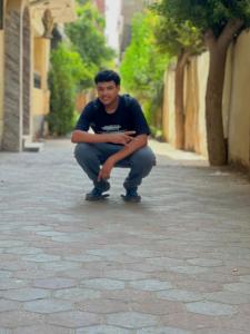 Un hombre en cuclillas en una calle de una ciudad. en Skyline Pyramids Hotel Inn, en El Cairo