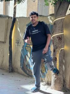 Un hombre parado junto a una pared con un árbol. en Skyline Pyramids Hotel Inn, en El Cairo