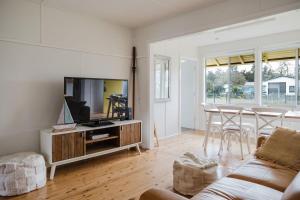 a living room with a tv and a couch at The Yellow Door Lakehouse in Green Island