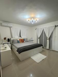ein weißes Schlafzimmer mit einem Bett und einem Deckenventilator in der Unterkunft Pretty Family house! In Punta Cana in Punta Cana