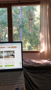 un computer portatile seduto su un letto di fronte a una finestra di CasaSur-37Robles-2 a Villa La Angostura