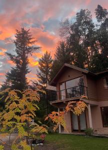 una casa con un tramonto sullo sfondo di CasaSur-37Robles-2 a Villa La Angostura