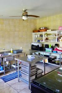 una cucina con tavoli e scaffali in una cucina di Pension Terehaunui Teahupoo a Teahupoo