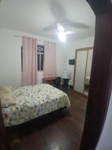 a bedroom with a bed and a window with pink curtains at Hospedagem São Pedro in Juiz de Fora