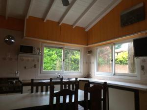 a kitchen with windows and a table and chairs at La casita in Villa Gesell