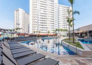 une piscine avec des chaises longues et un grand bâtiment dans l'établissement Solar das Águas Park Resort, à Olímpia