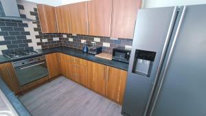 eine Küche mit Holzschränken und einem Edelstahlkühlschrank in der Unterkunft Ecclesfield Cottage - Two Bedrooms in Sheffield near Peak District with fast Wi-Fi, off-street parking and garden in Ecclesfield + 15 Fotos