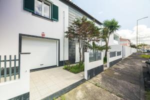 eine weiße Garagentür in einem weißen Haus in der Unterkunft Casa Moderna - New Stylish Home with Private Outdoor Space & AC - Near Beach & Shops in Ribeira Grande