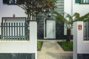 a building with a gate and a door with trees at Modern 3BR Home, AC in All Rooms, Walk to 2 Beaches, Private Patio, Washer & Dryer in Ribeira Grande