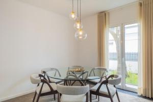 ein Esszimmer mit Glastisch und Stühlen in der Unterkunft Casa Moderna - New Stylish Home with AC & Patio - Near Beach & Shops in Ribeira Grande + 24 Fotos
