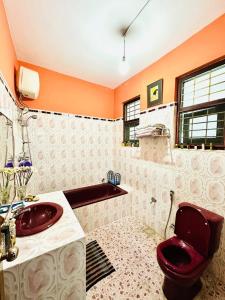 a bathroom with a red toilet and a sink at A Home Away B&B in Kiribatkumbura +5 photos