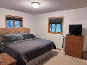 a bedroom with a bed and a flat screen tv at Spooner Shores - Wooded, Lakefront Retreat in Spooner