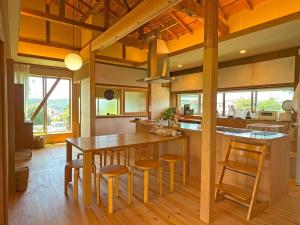 Una cocina con una mesa de madera y algunas sillas. en 広い縁側とタタミの部屋に天井吹抜けのオープンキッチンがある一軒家でキッチンやバスルームは最新設備, en Komoro