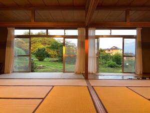 Habitación con ventana grande con vistas al patio en 広い縁側とタタミの部屋に天井吹抜けのオープンキッチンがある一軒家でキッチンやバスルームは最新設備, en Komoro