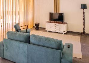 a living room with a blue couch and a tv at Fonte da Rosa Guest House Central Studio in Belmonte