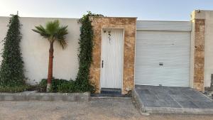ブライダにあるتريت ان فيلاの建物の隣にヤシの木がある白いガレージのドア +4枚の写真