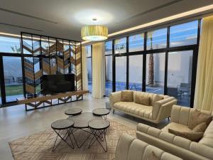 a living room with a couch and tables and a tv at اليجنت فيلا in Buraydah