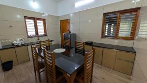 a kitchen with a table and chairs and a refrigerator at Grand Beach Villa in Kannur