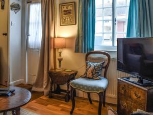 ein Wohnzimmer mit Sessel und Fernseher in der Unterkunft Lavenham Red Brick Cottage in Lavenham