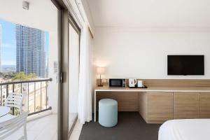 a bedroom with a desk with a tv and a balcony at Sea View Hotel Room Heart of Surfers Paradise in Gold Coast