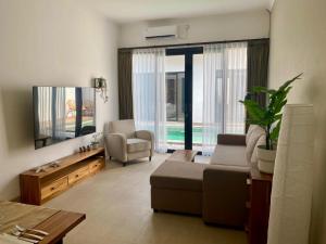 Una sala de estar con un sofá y un televisor. en Badung Villa no 4, en Ungasan