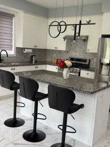 Una cocina con una encimera con cuatro taburetes de bar. en Comfy Basement Suite in Quiet Neighbourhood, en Whitby