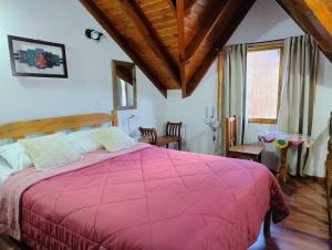 1 dormitorio con 1 cama grande y edredón rosa en Apart Ruta 40, en El Chaltén